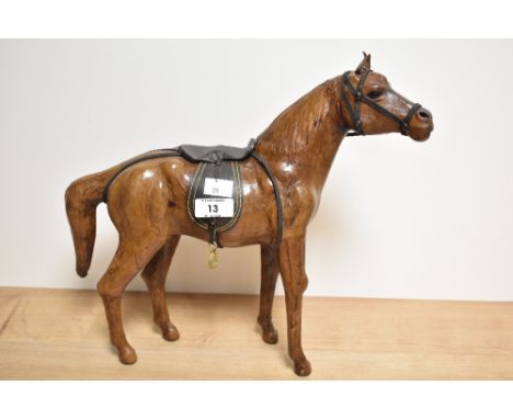 In the manner of Liberty &amp; Co, a stained leather covered horse figure with saddle, 31.5cm, some deterioration to reins.