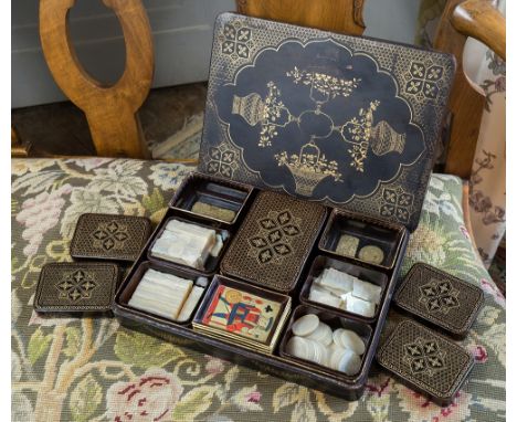  A late 19th century Indian papier mache gaming box, black lacquer with gilt floral urn and basket decoration within trellis 