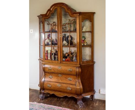  A 19th century Dutch walnut glazed cabinet, the shaped arched pediment above conforming astragal glazed double doors, shaped