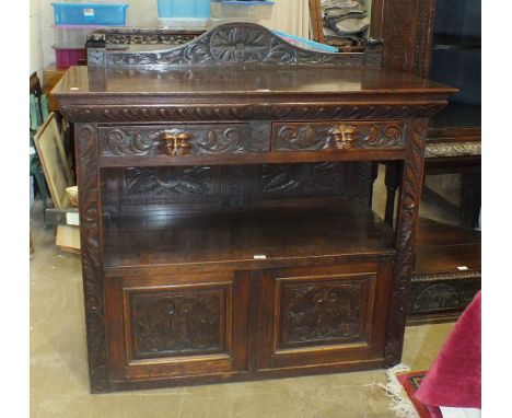 A Victorian carved oak two-tier buffet having a pair of frieze drawers above a shelf and two cupboard doors, 121 x 106cm.