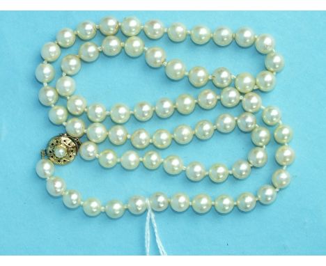 A string of seventy uniform cultured pearls with pearl-set gold clasp, (7mm diameter), 63cm long.