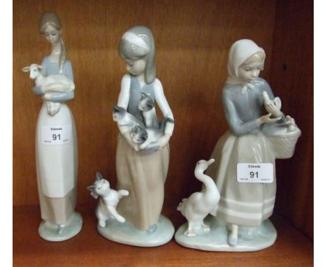 A Lladro figure of a young woman holding a lamb, 27cm, another of a young woman holding ducklings and one other, (3).