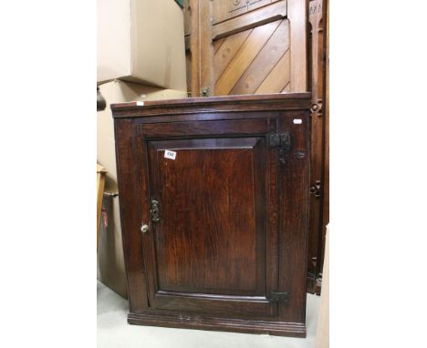 George III Oak Hanging Corner Cabinet, the single panel door opening to reveal two shaped shelves, with key, 82cms high x 66c