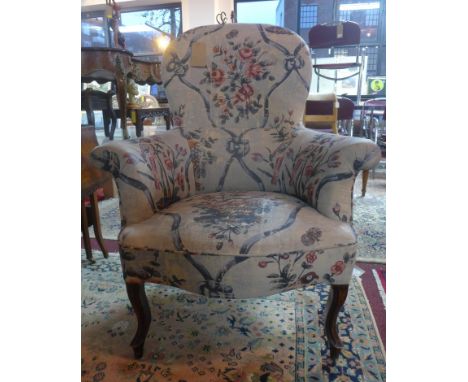 A late 19th century French spoon back armchair, with button back floral upholstery, raised on cabriole legs 