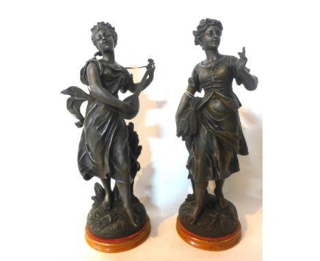 Two spelter figures of young ladies, one holding wheat sheaths and the other playing a lute, raised on giltwood and red velve