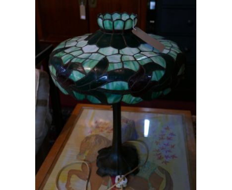 A Tiffany style leaded and stained glass lamp in shades of mottled green with dark red flowers, to a weighty naturalistic met