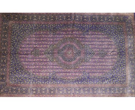 A Qum silk carpet with central floral medallion, on a purple ground, contained by floral motifs and borders, 205x132cm 