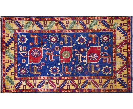 A Kazak carpet with triple geometric medallion, on a blue ground, contained by yellow geometric border, 200 x 141cm 