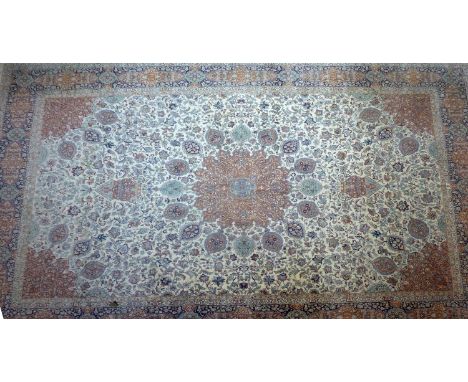 A large 20th century Qum carpet, with central floral medallion surrounded by floral motifs, on a beige ground, contained by f