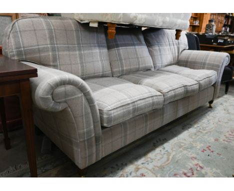 A Laura Ashely three seater sofa with straight back and scroll arms standing on turned legs with brass casters, grey/buff tar