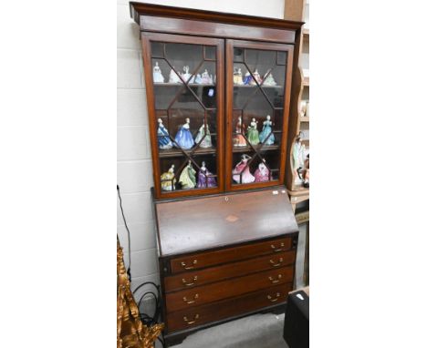 An Edwardian bureau bookcase with astragal glazed doors and fall front panel over four long drawers standing on bracket feet,