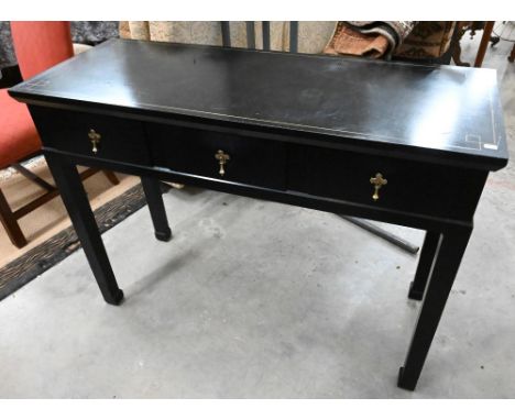 A black framed console table with gilt detailing, three drawers and square supports 