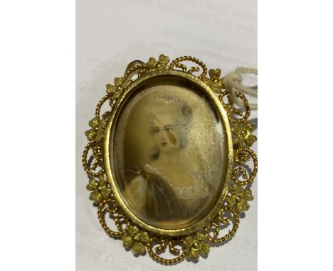 A late 19th/early 20th century portrait brooch with hand engraved and painted portrait of a lady on yellow metal with wire wo