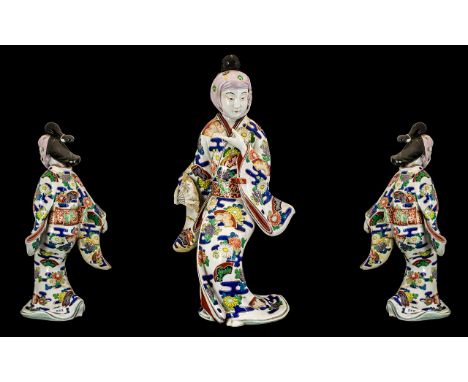 Japanese Antique Imari-Style Figure of a courtesan wearing a flowing gown, holding a fan in one hand. Highly decorated in col