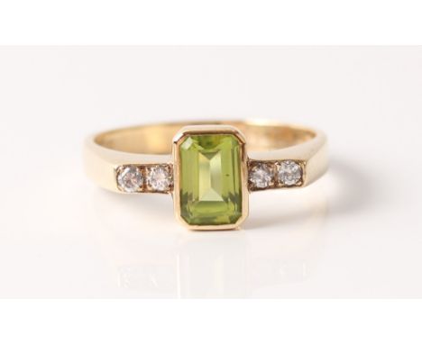 A hallmarked 9ct yellow gold peridot and diamond ring, set with a central emerald-cut peridot, flanked to either side with tw