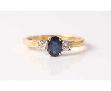 A hallmarked 18ct yellow gold three stone sapphire and diamond ring, set with a central oval cut sapphire, flanked to either 