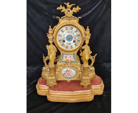 A French gilded mantle clock with female columns with two hand painted Sevres style panels of Cupid and cherubs and flowers o