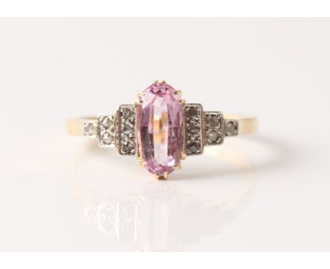 A pink stone and diamond ring, set with a central oval cut pink stone flanked to either side with diamond set stepped shoulde