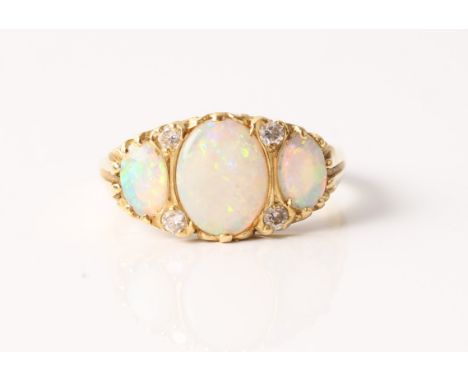 A hallmarked 18ct yellow gold opal and diamond ring, set with three oval opal cabochons spaced by four round brilliant cut di