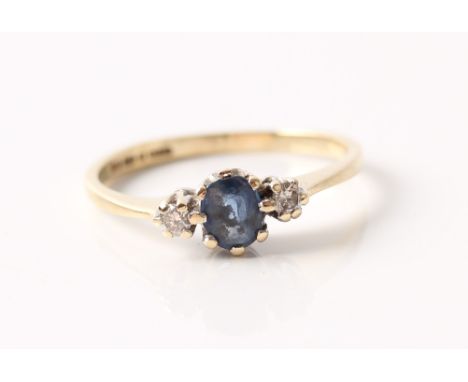 A hallmarked 9ct yellow gold sapphire and diamond three stone ring, set with a central oval cut sapphire, flanked to either s