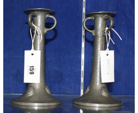 A pair of pewter candlesticks in the Arts and Crafts style, each with triple ring handles above Celtic knot style decorative 