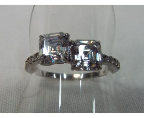 A white metal ring set with two stones and stone chips to the shank size R