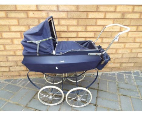 A vintage Silver Cross style pushchair with a hood cover and accessories bike