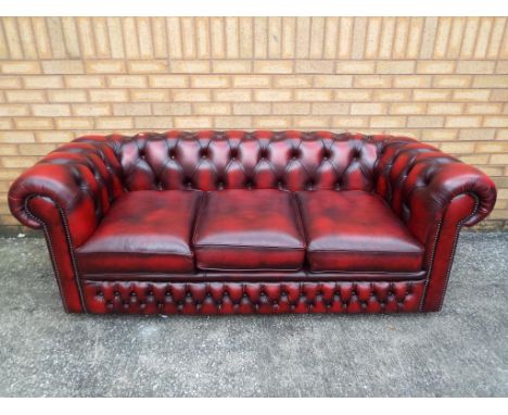 A three seat oxblood button back Chesterfield sofa with studded arm fronts, approximately  sofa is approximately 188 cm long,