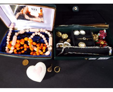 Two jewellery boxes containing a quantity of paired earrings, enamelled brooches, necklaces, a ceramic heart shaped trinket b