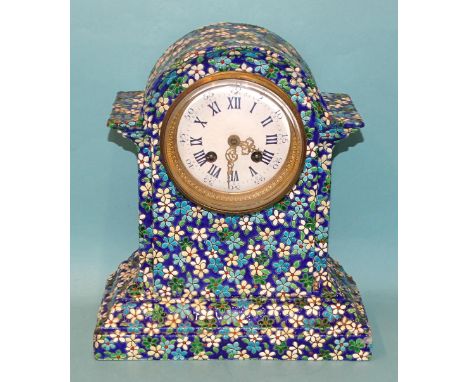 A ceramic mantel clock decorated with enamelled flower heads and leaves, the white enamel dial with Roman and Arabic numerals