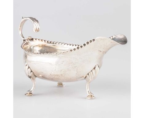 A GEORGE III SILVER CREAM BOAT by Hester Bateman, London 1787, with punched rim and leaf-capped scroll-form handle, raised on