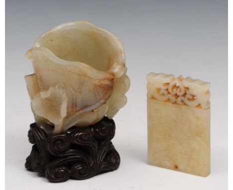 A jade lotus flower vessel  18th/19th Century on a hardwood stand and a Chinese jade small pendant, one side carved with a sc