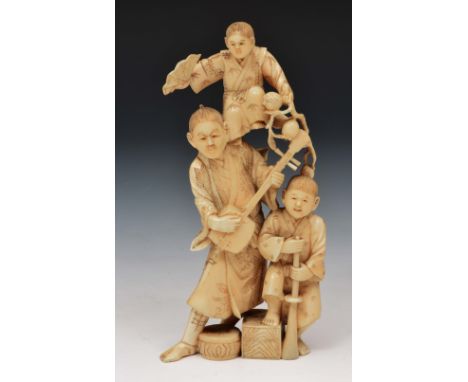 A Japanese walrus ivory okimono of a street entertainer Meiji period the entertainer playing a biwa while accompanied by two 