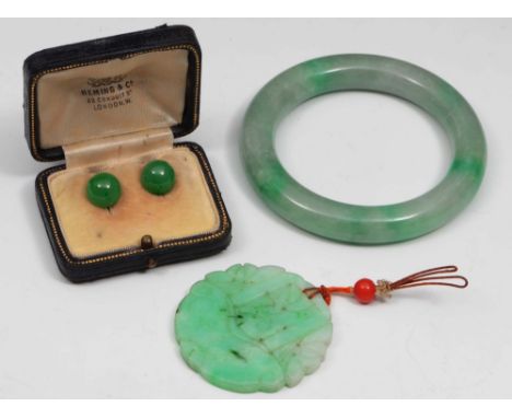 A jade bangle, a jade pendant and a pair of jade earrings the pendant carved with floral motifs, 5cm diameter, width of bangl