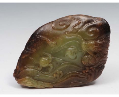 A Chinese green and brown jade boulder 18th Century carved with a coiled dragon, the reverse with swirls of clouds, 9.7cm lon