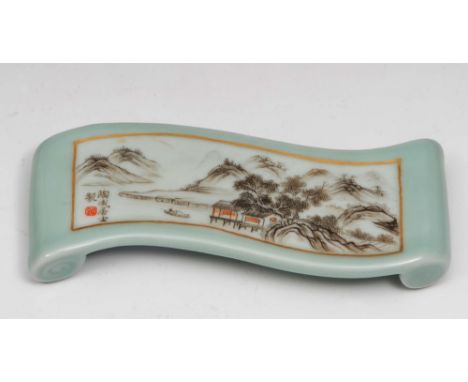 A Chinese porcelain celadon brush rest Republic period in the form of a hand scroll with a lake landscape in monochrome, red 