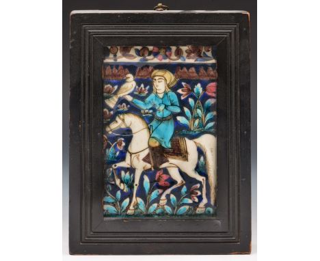 A Persian Qajar tile late 19th Century a Falconer on horseback on a blue ground with turquoise leaf decoration within an ebon