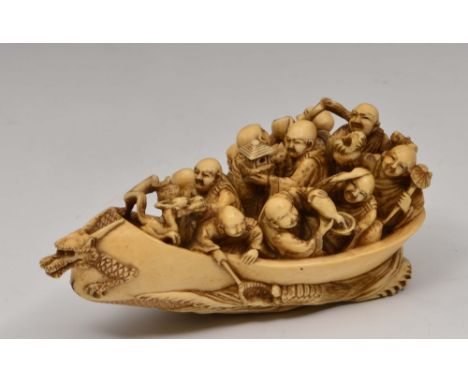 A Japanese ivory netsuke of a dragon boat late 19th Century signed Yasuaki, with ten Rakan on board, each holding a Buddhisti