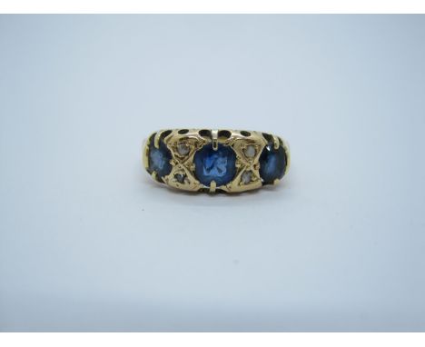 A Sapphire and Diamond Ring pavé-set three cushion-cut graduated sapphires with diamond points between, stamped 18ct, ring si