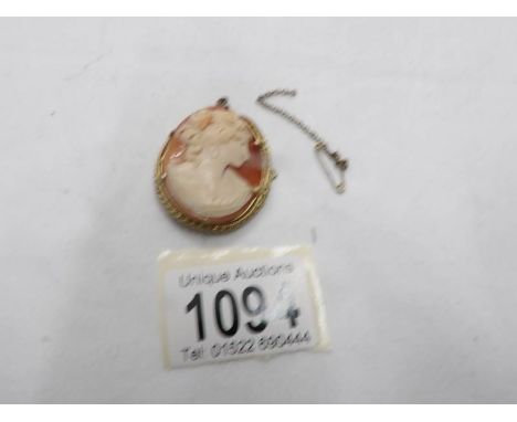 A vintage shell cameo brooch of female profile with safety chain,