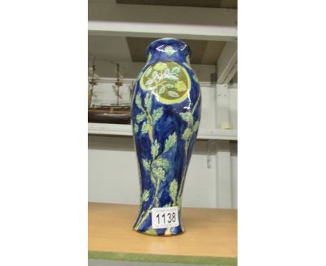 A Della Robbia 11.5" vase, blue background with leaves, signed by painter Hannah Jones, other marks on base include AEB and 2