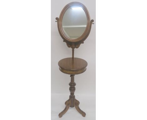 A 20TH CENTURY MAHOGANY OVAL SHAVING MIRROR ON STAND, with circular compartment with twin lids over a turned baluster column 