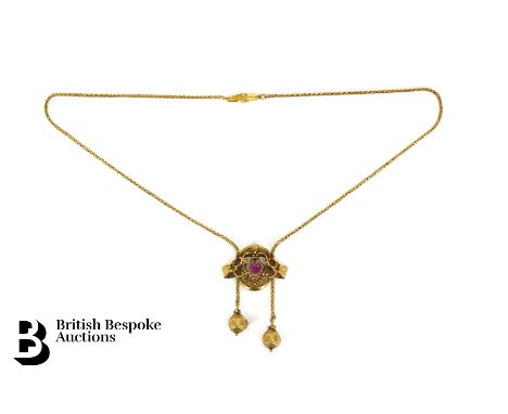 A Continental 18ct yellow gold ruby tassel drop pendant necklace. The mask set with an oval ruby measuring 6 x 5mm, with two 