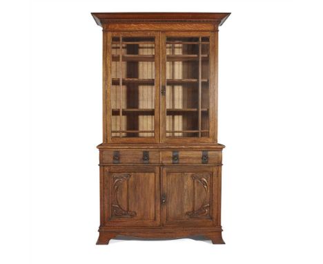 ENGLISH SCHOOL ARTS &amp; CRAFTS OAK BOOKCASE CABINET, CIRCA 1910 the projecting cornice above two glazed doors, opening to a
