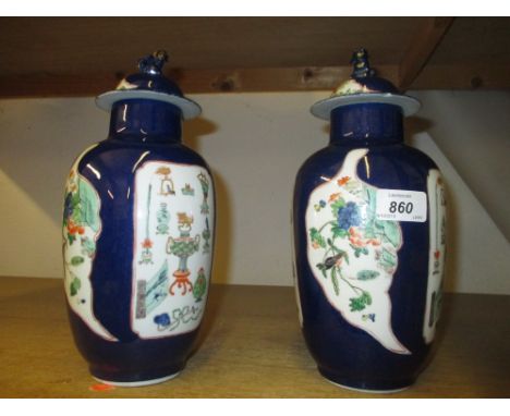 Pair of Oriental baluster form enamel and gilt decorated vases with panels of decoration on blue ground, the covers mounted w