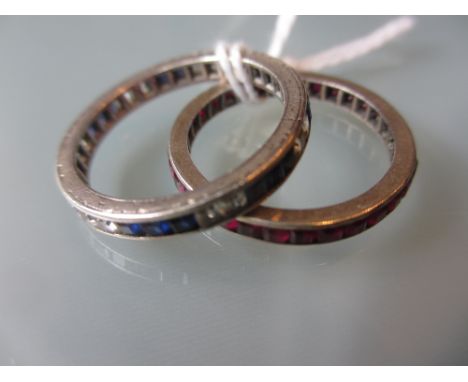 Eternity ring set alternating groups of square cut sapphire and diamonds together with a similar ruby set eternity ring