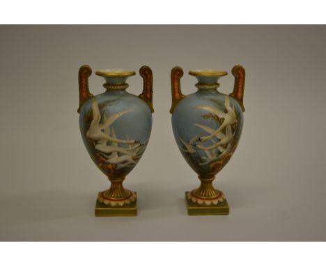 Pair of Royal Worcester baluster form two handled pedestal vases painted by Charles Baldwyn, each painted with swans in fligh