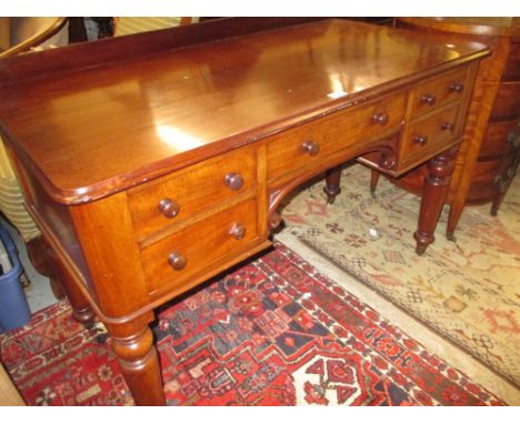 19th Century mahogany kneehole desk having galleried back above five drawers with knob handles, raised on turned tapering sup