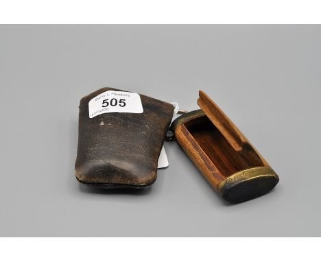 WOODEN SNUFF BOX WITH DECORATED BRASS ENDS IN LEATHER SLEEVE