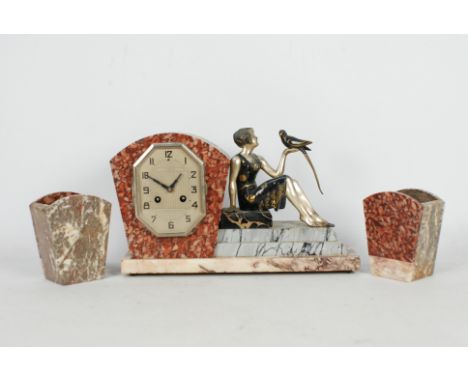 A French Art Deco styled clock garniture comprising of a sculpture of a seated figurine of a lady with a bird perched on her 